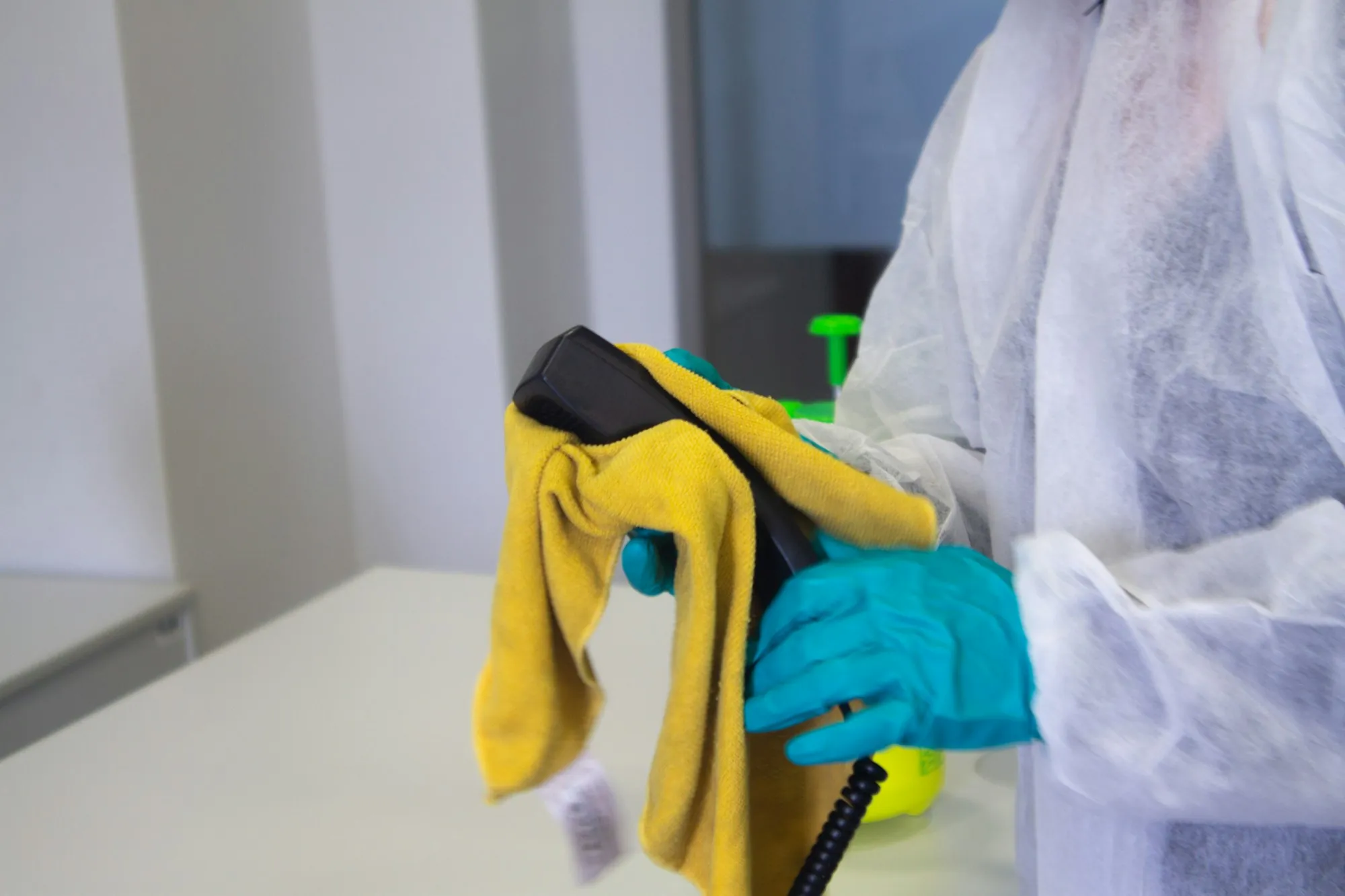 Worker in protective clothing wiping a surface with a cloth and spray
