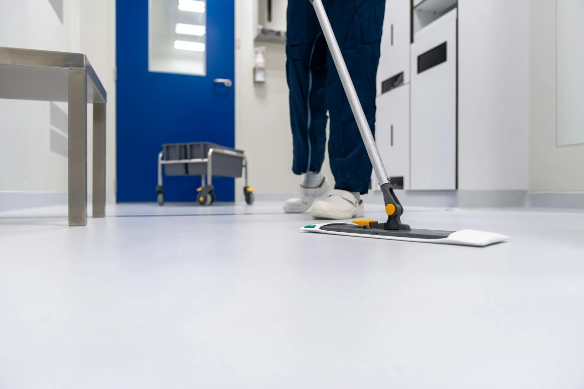 Cleaner dust mopping a bright white floor