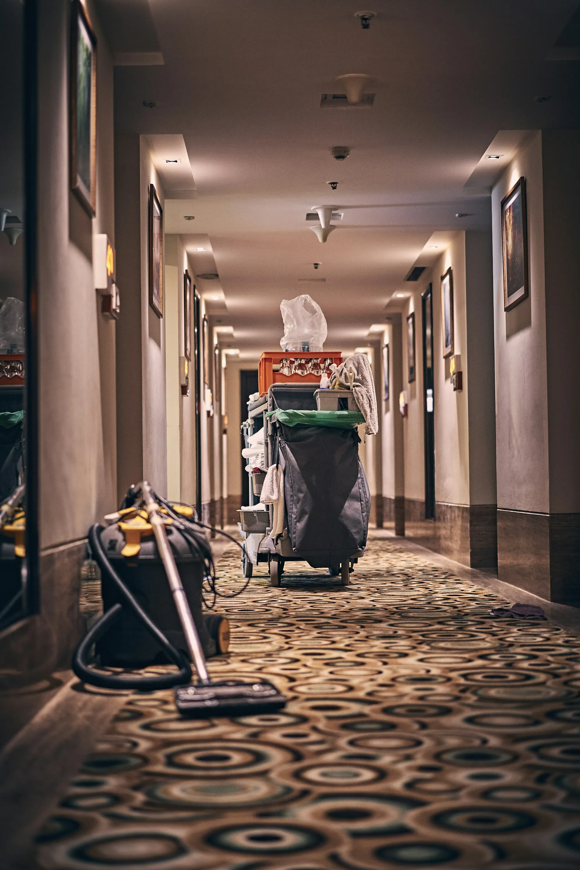 Housekeeping cart parked in a long carpeted building corridor